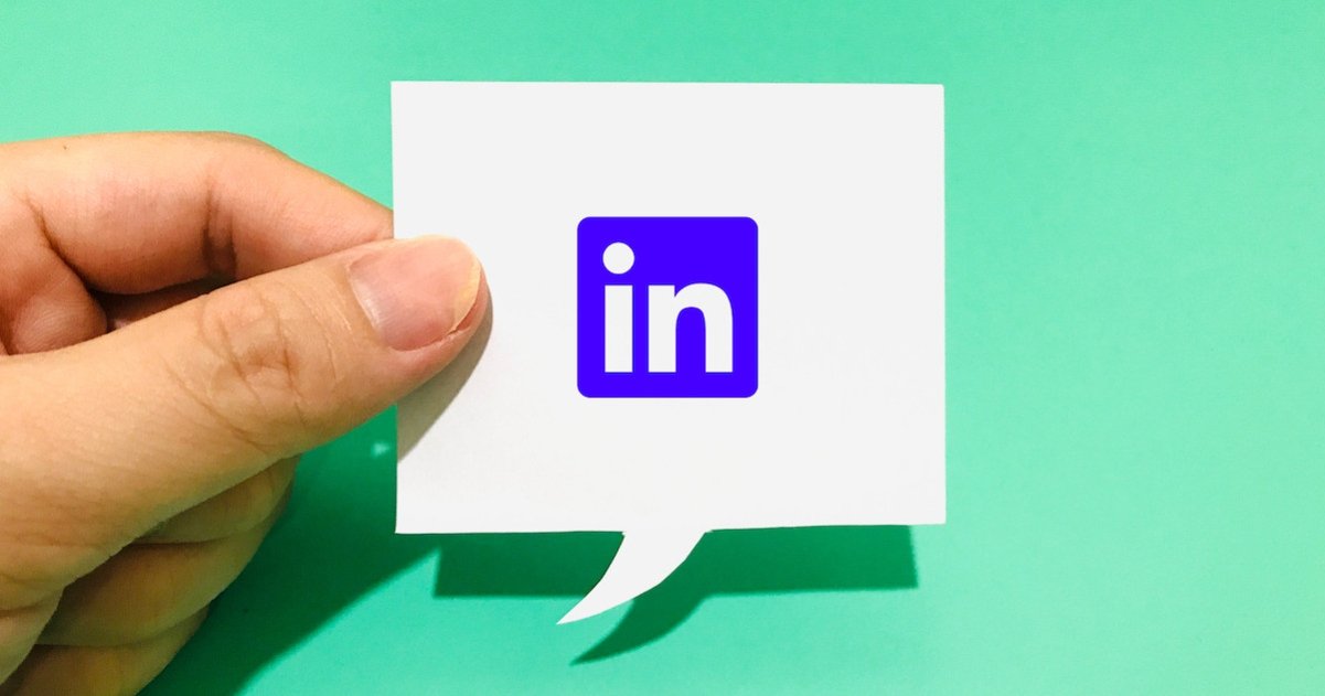 Logo de LinkedIn en papel sostenido por unos dedos