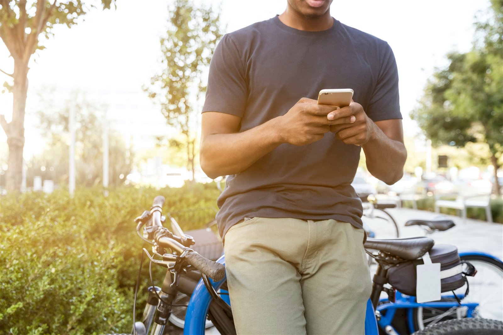 un hombre mira el móvil apoyado en una bici