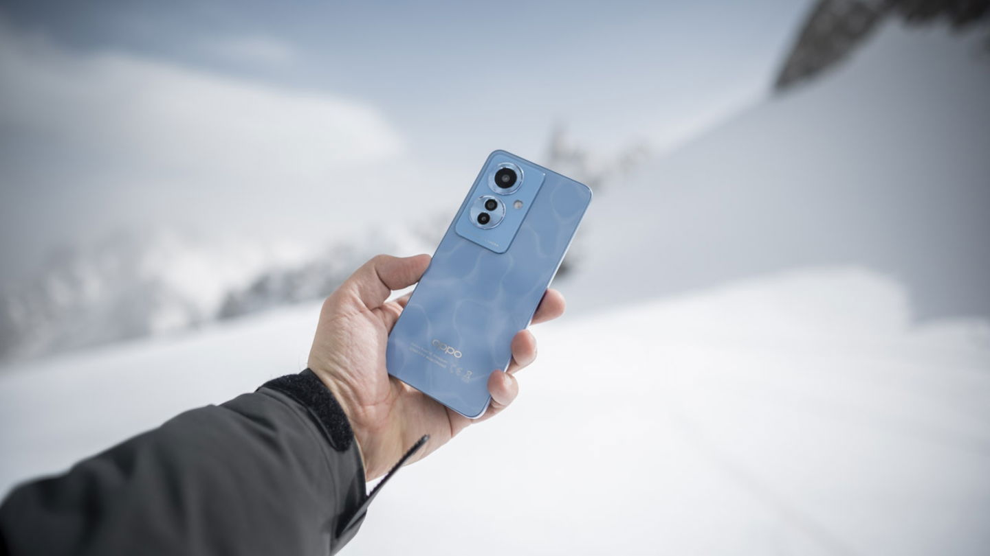 OPPO Reno11 F 5G en una mano masculina con una montaña nevada de fondo