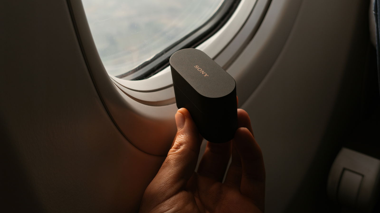 Estuche de los Sony WF-1000XM6 en la ventanilla de un avion